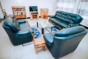 una sala de estar con 2 sofás de cuero y una mesa. en Peace Guest House en Muhari
