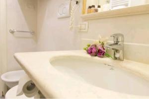 een witte badkamer met een wastafel met bloemen erop bij Ca Briani DX in Venetië