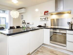 una cocina con armarios blancos y electrodomésticos de acero inoxidable en 6 person holiday home in V ggerl se en Bøtø By
