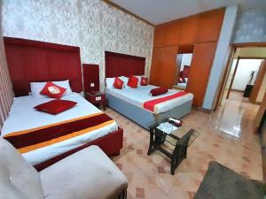 una habitación de hotel con 2 camas y una silla en Hotel Super Seven, en Lahore