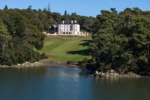 een groot wit huis op een heuvel naast een rivier bij Domaine de Locguénolé & Spa - Relais & Chateaux in Kervignac