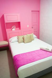 różowa sypialnia z dużym łóżkiem z różowym zagłówkiem w obiekcie Hotel Chromatic w mieście Guatapé