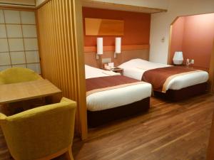 ein Hotelzimmer mit 2 Betten und einem Stuhl in der Unterkunft JR Hotel Clement Tokushima in Tokushima