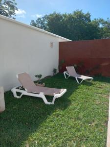 two lounge chairs sitting on the grass next to a wall at Villas Carlota Cancún in Cancún
