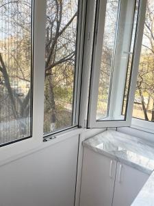 2 Fenster in einer Küche mit weißen Schränken in der Unterkunft Apartment Dzerzhinskogo in Öskemen