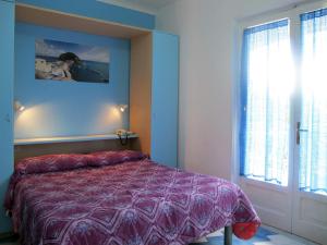 a bedroom with a bed with a purple comforter and a window at Aparthotel Villa Marinù in Ischia