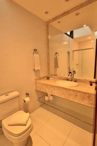 a bathroom with a sink and a toilet and a mirror at Hotel Home Green Home in Campos do Jordão