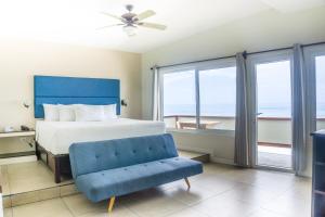 ein Schlafzimmer mit einem Bett und einem blauen Stuhl in der Unterkunft Hotel Roca Sunzal in La Libertad