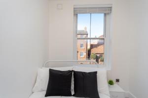 a white bed with black pillows in front of a window at Central Two Bed Flat Kings Lynn in King's Lynn