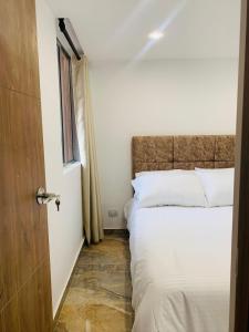 a bedroom with a bed with white sheets and a window at Alquiler Apartamento en Bogotá cerca al aeropuerto-Colibri Dorado in Bogotá
