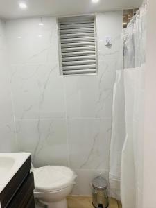 波哥大的住宿－Alquiler Apartamento en Bogotá cerca al aeropuerto-Colibri Dorado，白色的浴室设有卫生间和窗户。