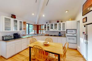 a kitchen with white cabinets and a wooden table and chairs at The Choli House in Crescent City