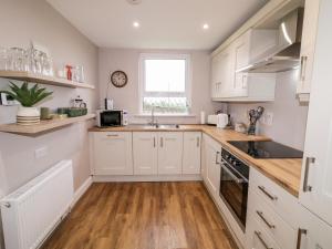 een keuken met witte kasten, een wastafel en een raam bij Rose Cottage in Omagh