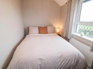 Cama en habitación pequeña con ventana en Rose Cottage, en Omagh