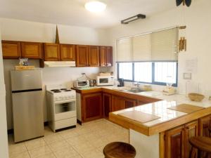 a kitchen with wooden cabinets and a white refrigerator at DON CARLOS PLACE 2nd UNIT in Alajuela City