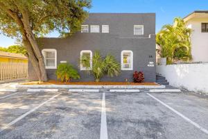 aphalt parking lot in front of a gray house at Bloom Hideaway - Mins to Las Olas & Beach in Fort Lauderdale