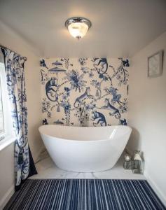 een wit bad in een badkamer met blauw en wit behang bij Kekaroka Lodge, Tottergill Farm in Brampton