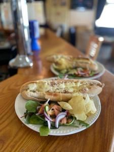 two plates of sandwiches and chips on a table at Cosy room with golf & the beach on your doorstep! in Mawgan Porth