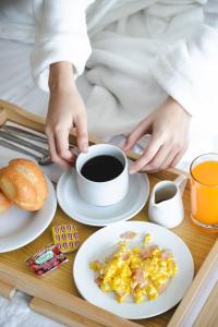 a person holding a cup of coffee and a tray of breakfast foods at Hotel Santa Rosa in Chiclayo