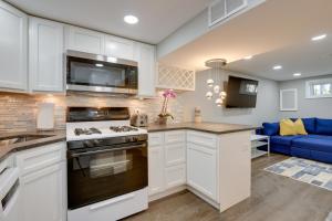 a kitchen with white cabinets and a blue couch at Convenient Washington, DC, Studio Near Metro Stop! in Washington, D.C.