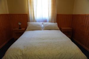 1 cama en un dormitorio con 2 mesas y una ventana en Hostal Puritama, en San Pedro de Atacama