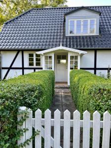 a white fence in front of a white house at Strandby 1847 B&B in Nykøbing Falster