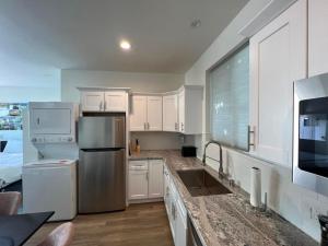a kitchen with white cabinets and a stainless steel refrigerator at Beach Apartment in Huntington Beach