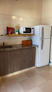 a kitchen with a white refrigerator and a microwave at Cabañas La Suyana in Tafí del Valle