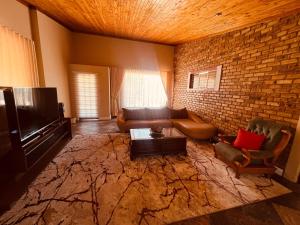 a living room with a couch and a brick wall at Langerman Lookout: Inviting Home with Rustic Charm and Modern Comfort in Johannesburg