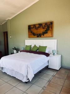a bedroom with a large white bed with green pillows at Langerman Lookout: Inviting Home with Rustic Charm and Modern Comfort in Johannesburg