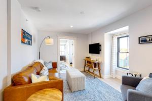 a living room with a brown leather couch and a tv at Fun in the Sun in Provincetown