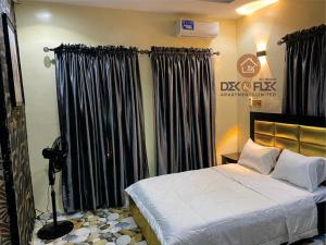 a bedroom with a large bed with black curtains at Dex & Flex Apartments 2 in Ibadan