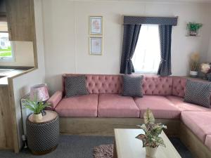 a living room with a pink couch and a table at The Wardens Retreat - Tattershall Lakes Country Park in Tattershall
