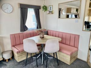 a dining room with a table and two pink chairs at The Wardens Retreat - Tattershall Lakes Country Park in Tattershall
