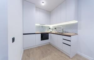 een witte keuken met witte kasten en een houten vloer bij Luxury apartment near metro station Osokorky in Kiev