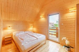a bed in a wooden room with a window at Nadmorska House in Grzybowo