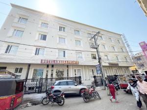 un grand bâtiment blanc avec des motos garées devant lui dans l'établissement Hotel AMBIKA PALACE PURI, à Purî