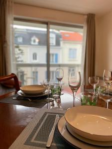een tafel met borden en wijnglazen en een raam bij Le Joan Miro - 100m des thermes in Vichy