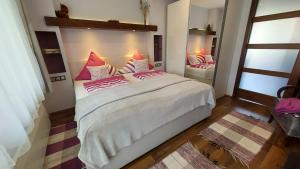 a bedroom with a large bed with pink pillows at Titi Boutique Apartmanok in Bükfürdő