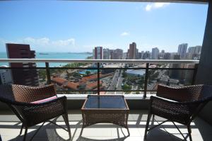 two chairs and a table on a balcony with a view of a city at Leme Penthouse Apartment in Fortaleza
