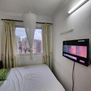 a bedroom with a tv and a bed and a window at The Majestic Royal Palms, Mtwapa in Shimo la Tewa