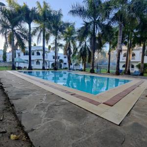 a swimming pool with palm trees in front of a house at The Majestic Royal Palms, Mtwapa in Shimo la Tewa