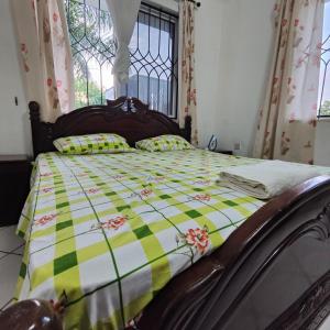 a bedroom with a bed with a green and yellow quilt at The Majestic Royal Palms, Mtwapa in Shimo la Tewa
