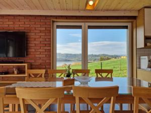 une salle à manger avec une table, des chaises et une grande fenêtre dans l'établissement Nad Zalew, à Sromowce Wyżne