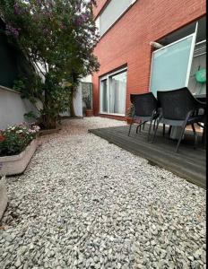 a patio with two chairs and a table and a building at Piso con jardín en Liencres in Liencres