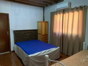 - une chambre avec un lit doté de draps bleus et d'une fenêtre dans l'établissement Chácara com 2 piscinas e 3 suítes, à Campo Grande
