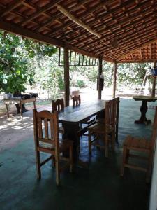 une table et des chaises en bois sous un toit en bois dans l'établissement Chácara com 2 piscinas e 3 suítes, à Campo Grande