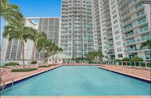 a large swimming pool with palm trees and tall buildings at Iconic 1BR loft Brickell-Waterviews in Miami