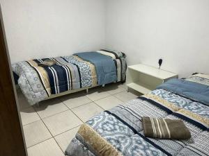 a bedroom with two beds and a tiled floor at Cs 3 qts, Brasília, Taguatinga. in Brasília