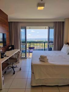 a hotel room with a bed and a desk with a view at Vision otima localização vista incrível e muitas comodidades in Brasilia